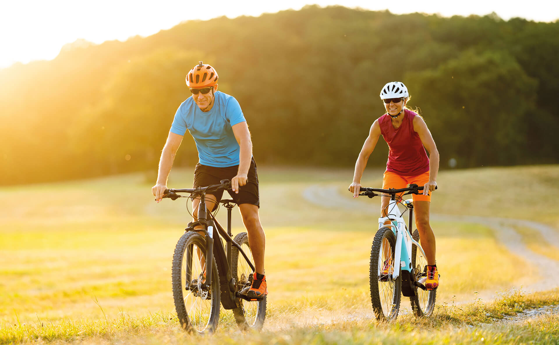 Zwei Personen fahren auf dem Fahrrad über ein Feld.